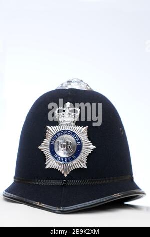 Real British Metropolitan Polizist Hut / Helm auf einfarbigem weißen Hintergrund mit Nahaufnahme Detail des Abzeichen Stockfoto