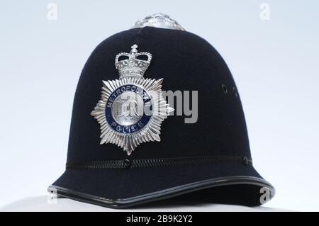 Real British Metropolitan Polizist Hut / Helm auf einfarbigem weißen Hintergrund mit Nahaufnahme Detail des Abzeichen Stockfoto