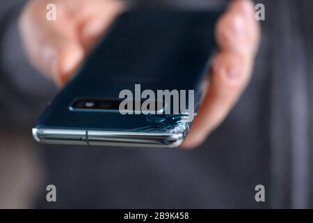 Mann hält modernes Smartphone mit gerissener Ecke in der Hand Stockfoto