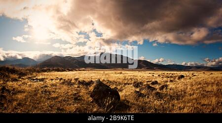 Dramatische Wolken über einer Landschaft von Bergen und grasigen Feldern Stockfoto