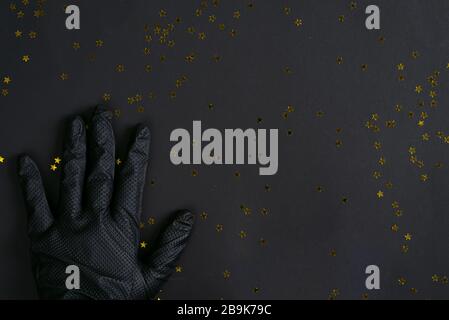 Hand der Frau in einem schwarzen Gummihandschuh zur Reinigung auf demselben Farbhintergrund, Kopierraum. Stockfoto