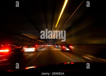 POV der Heckleuchten im Auto verschwimmen während der Fahrt durch den Tunnel Stockfoto