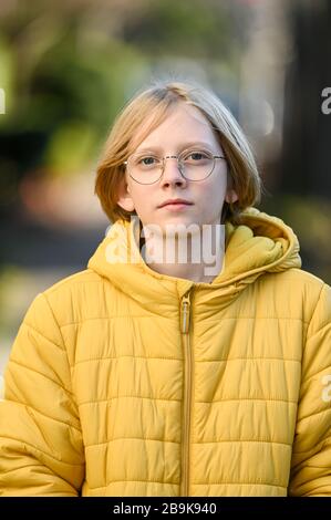 Tween Junge mit Brille und gelbe Jacke lächelnd Blick auf Kamera Stockfoto