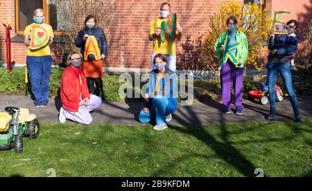 München, Deutschland. März 2020. Mitarbeiter des Kinderhauses Atemreich tragen gespendete Gesichtsmasken und halten Briefe in der Luft, die das Wort "Danke" bilden. Das Münchner Kinderhaus Atemreich hatte am Wochenende die Menschen über soziale Medien gebeten, während der Corona-Krise Schutzmasken für sie zu nähen. Im Kinderhaus leben 18 schwer kranke Kinder, die Atempflege benötigen. Die Masken sollen die kleinen Patienten schützen. Credit: Sven Hoppe / dpa / Alamy Live News Stockfoto