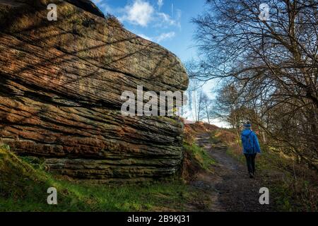 Person, die einen Winterspaziergang im Shipley Glen mit riesigen Felsbrocken in wunderschönem Licht, West Yorkshire, England, Großbritannien, macht Stockfoto