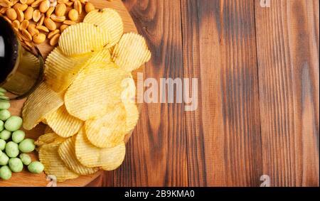 Bier in einer Flasche mit trockenem salzigen Snack, auf einem Holztisch mit freiem Platz. Stockfoto