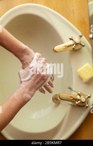 Frau wäscht ihre Hände mit Seife an einem Waschbecken von oben Stockfoto
