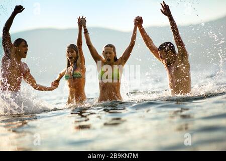 Eine Gruppe von Freunden, die unter Wasser hochspringen und die Hände halten. Stockfoto
