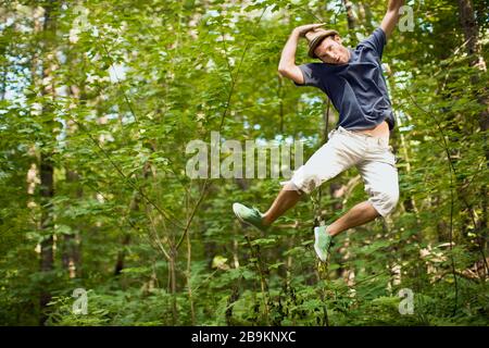 Junger Mann, der in der Luft in einem Wald springt Stockfoto