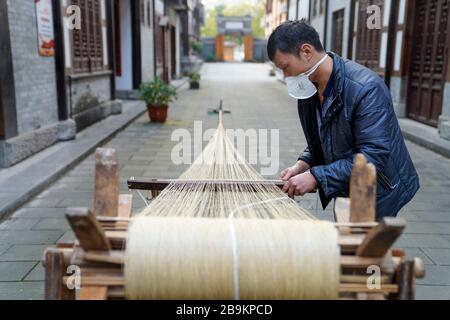 (200324) -- CHONGQING, 24. März 2020 (Xinhua) -- EIN Techniker macht Rongchang Grass Linen, auch Rongchang Xiabu genannt, in einem Workshop im Rongchang District in Chongqing, Südwestchina, 23. März 2020. Rongchang Grass Leinen ist ein traditionelles chinesisches Handwerk mit einer reichen Geschichte. Es ist eine Art Tuch, das rein von Hand aus Ramie besteht und berühmt ist für seine weiche, dünne, flache Textur und feine Qualität. Da dieses Tuch den Körper normalerweise im heißen Sommer kühl hält, wird es auch Xiabu (wörtlich Sommertuch) genannt. Mit umfassenden epidemischen Präventionsmaßnahmen macht Xiabu hier Industrien Stockfoto