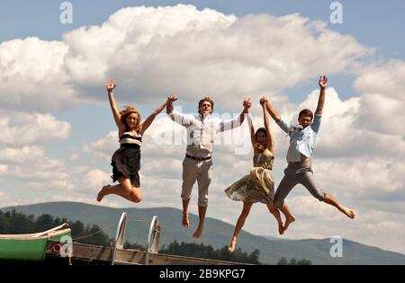 Vier Freunde halten die Hände und springen in die Luft. Stockfoto