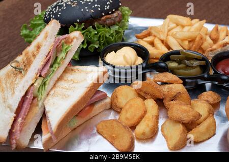 Ein amerikanischer Schwarzburger mit frittierten Kartoffeln auf dem weißen Tablett Stockfoto