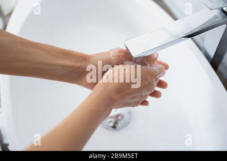 Frau aus der Nähe, die im Bad unter fließendem Wasser die Hände wascht Stockfoto