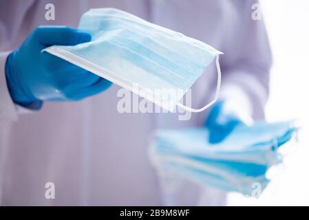 Junger Mann in medizinischen Bräuchen und Gesichtsmaske mit Gesichtsmaske. Konzept Infektionsschutz von Covid-19 Coronavirus Stockfoto