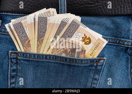 Viele polnische Banknoten mit einem Nennwert von 200 PLN sind in die hintere Tasche der blauen Jeans-Hose gesteckt. Stockfoto