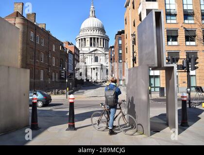 Mann mit Fahrrad wartet an einem sonnigen Tag an der Ampel im Zentrum Londons, die Stadt sieht verlassen aus. Stockfoto