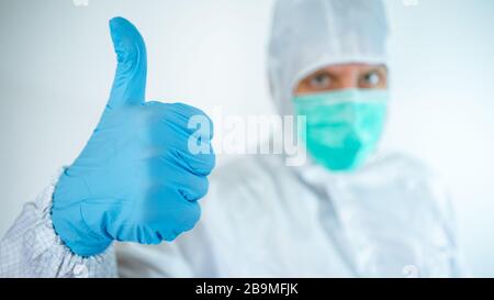 kaukasischer Arzt mit Schutzanzug und Maske, der eine Geste mit Ja unterschreibt, was zu einer positiven Signalwirkung führt. Schließen Sie die Viruserkrankung ab. Isoliert auf weißem Hintergrund. Stockfoto