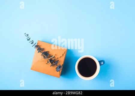 Mama liebt Sie auf einer dekorativen Platte neben einer Tasse Kaffee und Eukalyptus auf blauem Hintergrund. Stockfoto