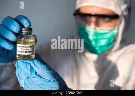 Wissenschaftlicher Mann mit Schutzanzug hält einen Impfstoff gegen Coronavirus. Kaukasischer Mann mit Impfung für COVID-19. 2019-nCoV in Wuhan China gefunden. Epi Stockfoto