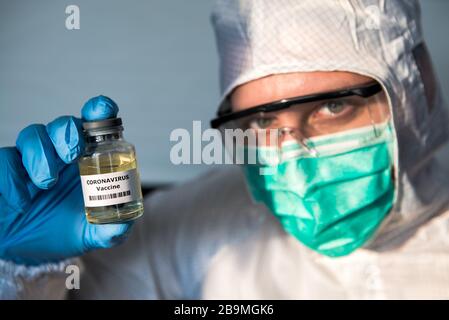 Männlich wissenschaftlicher Schutzanzug mit einem Impfstoff-Fläschchen-Coronavirus, medizinisches Konzept kaukasischer Mann mit Impfung Kovid 19 Injektionsbehandlung Diseas