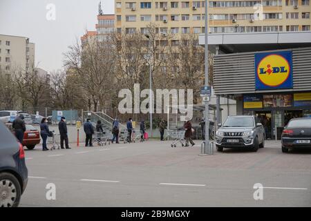 Bukarest, Rumänien - 24. März 2020: Moderate Warteschlangen von Menschen warten in Reihe vor einem Lidl-Supermarkt, nachdem ein Coronavirus Sperrwerk angekündigt wird. Stockfoto