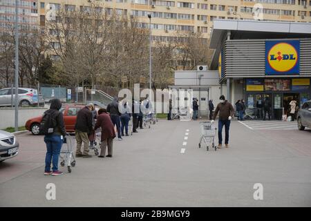 Bukarest, Rumänien - 24. März 2020: Die Menschen warten in Reihe vor einem Lidl-Supermarkt, nachdem ein Coronavirus-Lockdown angekündigt wird. Stockfoto