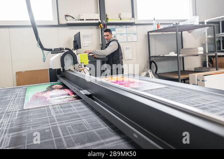 Der Techniker der Druckerei arbeitet an einer großen CNC-Computer- numerischen Steuerungs- und Schneidemaschine Stockfoto