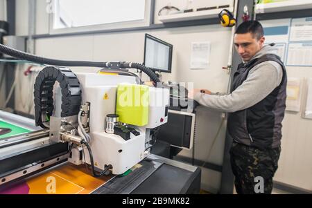 Der Techniker der Druckerei arbeitet an einer großen CNC-Computer- numerischen Steuerungs- und Schneidemaschine Stockfoto