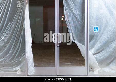 Blick durch die Glastür des leeren und geschlossenen Geschäftsgebäudes, das renoviert wird Stockfoto