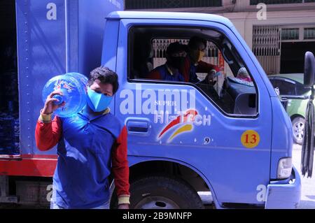 Gereinigtes Wasser wird von einem kambodischen Arbeiter geliefert, der während der Coronavirus-Pandemie Phnom Penh, Kambodscha, eine Gesichtsmaske trägt. © Kraig Lieb Stockfoto