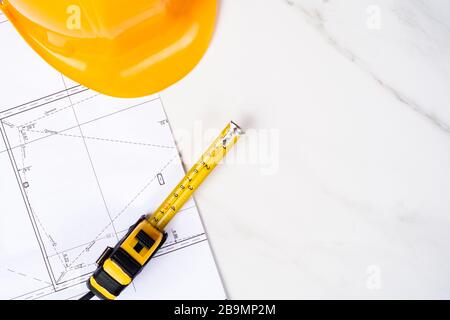 Nahaufnahme von Blaupausen, Messband und gelbem Bauhelm. Ingenieurkonzept Stockfoto