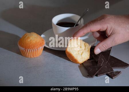 Hand greifen halb gefressene Muffin mit Tasse Schokolade Stockfoto