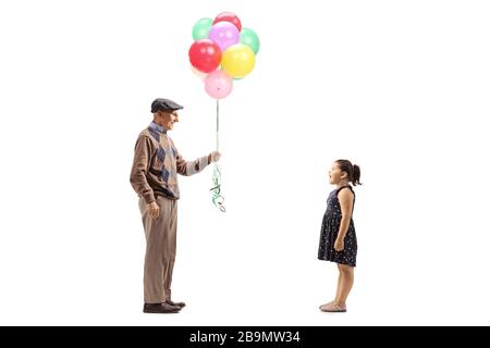 Profilaufnahme in voller Länge eines Großvaters, der der Enkelin auf weißem Hintergrund bunte Ballons schenkt Stockfoto