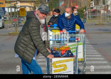 Nahaufnahme eines Kunden in einer Schlange außerhalb des Lebensmittelladens. Mann trägt Corona-Virus-Schutzmaske, Einkaufswagen für Grundbedürfnisse in Pandemie-Kovid1 Stockfoto