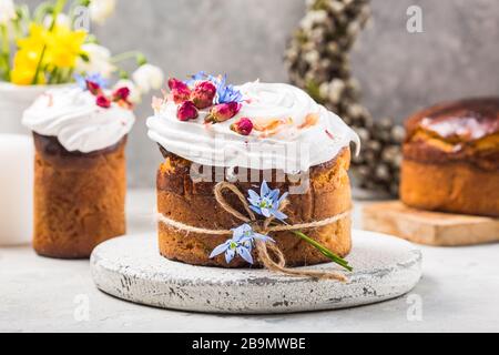 Osterkuchen - Russisch und Ukrainisch traditionell Kulich oder Brioche auf hellem Steingrund. Paska- oder Panettonbrot und Frühlingsblumen Stockfoto