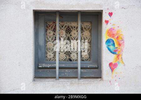 Graffiti. Bunte dekorative Straßenkunst an der Wand neben einem kleinen Wohnungsfenster im Pariser Stadtteil Butte aux Cailles. Frankreich. Stockfoto