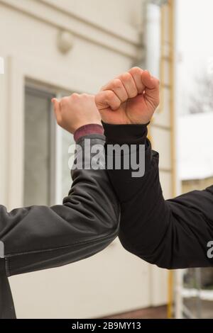 Freunde schütteln Ellbogen im Freien. Menschen begrüßen zusammen mit einem neuen Stil, um Coronavirus zu verhindern. Schütteln Sie die Hände nicht. Ellenbogenbegrüßungsstil. Halten Sie Handschak an Stockfoto