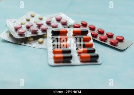 Mehrfarbige Pillen und Kapseln in Blisterpackungen im Nahbereich, auf blauem Hintergrund.Soft Focus .das Konzept der Behandlung von menschlichen Krankheiten. Stockfoto