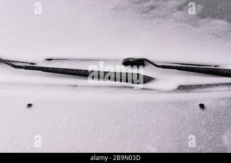 Schneebedeckte Windschutzscheibe mit Wischerblättern. Konzept des Fahrens im Winter mit Schnee auf der Straße. Wintersaison. Stockfoto