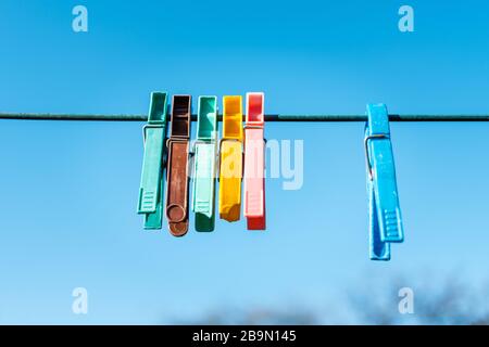 Sechs Wäscheklappen, die an einer Linie gegen einen reichen blauen Himmel hängen Stockfoto