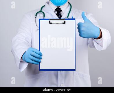 Hausarzt in weißem Mantel, blaue Latexhandschuhe, Stethoskop am Hals, Arzt mit Papierhalter mit weißem leerem Blatt, Platz für wri Stockfoto