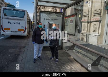 Zwei Reinigungskräfte warten während der Zeit der Einschließung auf den Bus, der sanitäre Masken trägt. Barcelona steht vor seinem zehnten Tag der Einschließung, der von der spanischen Regierung aufgrund der Ausbreitung des Coronavirus beschlossen wurde. Stockfoto