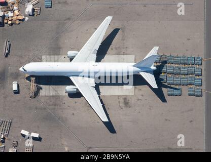 Luftaufnahme von nicht identifizierbaren Flugzeugen für den Güterverkehr mit umgehenden Frachtpaletten. Von oben gesehen, weißes Frachtflugzeug. Stockfoto