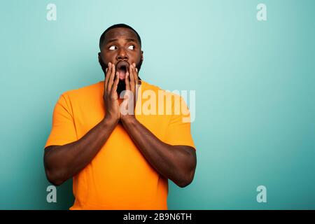 Erstaunt und Ausdruck einer jungen über cyan Hintergrund schockiert Stockfoto