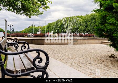 Szczecin, Polen, Juni 2018 traditionelle Metallbank und Springbrunnen auf dem Jasne Blonia Platz, in der Nähe der Stettiner Stadtverwaltung. Menschen, die sich in einem Park entspannen Stockfoto