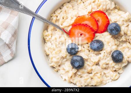 Schüssel Haferbrei Haferbrei mit Erdbeeren und Blaubeeren. Draufsicht. Stockfoto