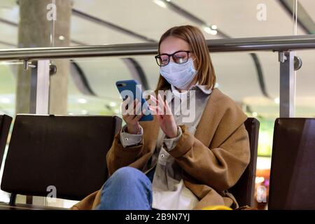 Frau verärgert über die Flugannullierung, schreibt Nachricht an Familie, sitzt in fast leerem Flughafenterminal wegen Coronavirus-Pandemie/Covid-19-Ausbruch Stockfoto