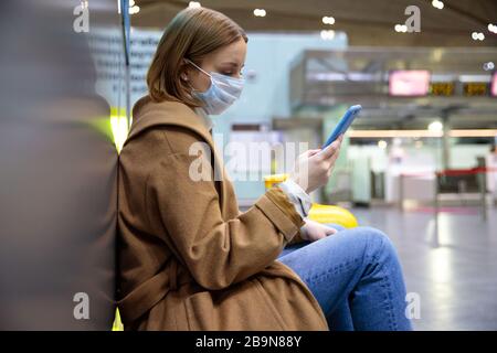 Frau verärgert über die Flugannullierung, schreibt Nachricht an Familie, sitzt in fast leerem Flughafenterminal wegen Coronavirus-Pandemie/Covid-19-Ausbruch Stockfoto