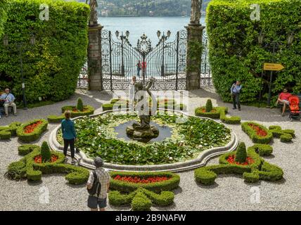 TREMEZZO, COMER SEE, ITALIEN - JUNI 2019: Menschen, die das Wasserspiel bewundern und Kästenhecken in der Villa Carlotta in Tremezzo am Comer See beschnitten haben Stockfoto