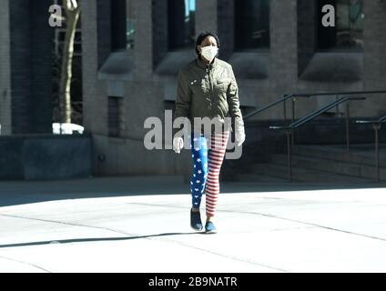 Manhattan, New York, USA. März 2020. Frau, die auf Straßen mit Maske spazieren geht und eine Hose mit US-Flagge trägt. Zweitens, nachdem die New Yorker Behörden angeordnet hatten, zu Hause zu bleiben, außer denjenigen, die wichtige Dienstleistungen erbringen. 24.03.20. New York Manhattan 99 ST und Madison AV. Marcus Santos. Kredit: Marcus Santos/ZUMA Wire/Alamy Live News Stockfoto